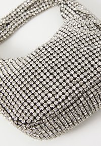 Borsa con applicazioni di strass, dalla forma arrotondata e base in tessuto nero; presenta una superficie morbida e texturizzata con accenti metallici scintillanti.