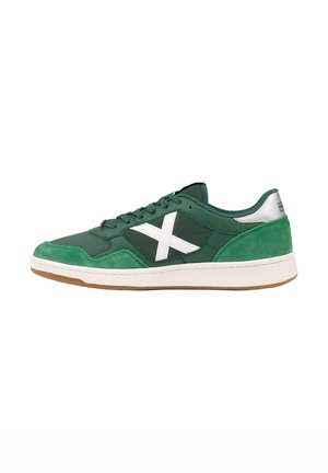 Zapatilla deportiva verde de corte bajo con suela blanca y logo X blanco en el lateral, con materiales de ante y malla y cordones verde oscuro.