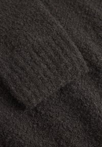 Sötétszürke, textúrált szövet, puha, bolyhos felülettel; bordázott részletek találhatók benne, amelyek mélységet adnak az anyagnak.