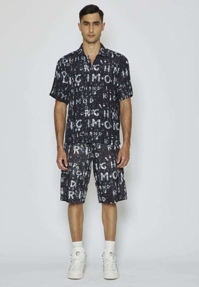 Maglietta nera a maniche corte e pantaloni abbinati con una stampa grafica bianca che presenta la parola "RICHMOND" in dimensioni variabili sul tessuto.