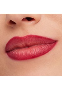 Nærbilde av lepper med en matt dyp rød farge, jevn tekstur, definert form, og klar leppelinje. Subtil glans fremhever midten.