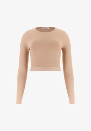 Haut cropped à manches longues de couleur beige clair en tissu lisse et extensible, avec un col rond et une bande de logo visible à l'ourlet.
