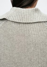 Heleroosa kootud kardigan soonikkoega kraega, millel on lõtv kootud tekstuur ja lihtne, kaunistusteta disain.