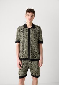 Men’s matching set featuring a short-sleeve, collared shirt and shorts. Knitted fabric in green with black accents and a textured pattern.