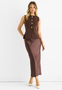 Brown sleeveless top with gold buttons, paired with a long brown satin skirt. Both garments feature a smooth texture and tailored fit.