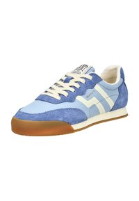 Lichtblauwe en marineblauwe sneaker met witte veters, beige zool en witte zigzagstrepen aan de zijkant, met merknaam "GANT" op de tong en zijkant.