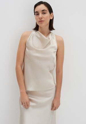 Haut sans manches à col bénitier en satin beige clair avec une finition texturée. Drapé doux et silhouette fluide, associé à une jupe assortie.