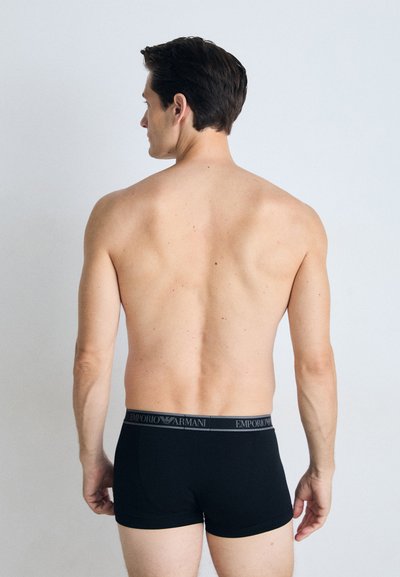 Černé bavlněné boxerky s šedým elastickým pasem, na kterém je logo "Emporio Armani". Model je zobrazen zezadu.