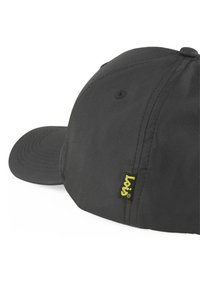 Gorra negra fabricada con tela suave y con visera curvada. Presenta una etiqueta de logo amarilla a un lado y un agujero de ventilación cosido en la parte superior.