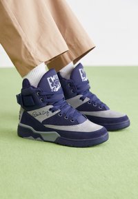 Baskets montantes en daim bleu marine et textile gris, dotées d'une cheville rembourrée, d'une fermeture à lacets et de logos contrastants sur la languette et le côté.