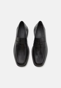 Schwarze Lederloafers mit glatter Oberfläche, quadratischer Zehenform und einem dekorativen Riemen über dem Spann. Leichte Gummisohle für Komfort.