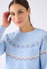 Maglione lavorato a maglia di un azzurro chiaro, realizzato in lana morbida con un motivo testurizzato; presenta disegni geometrici in crema, arancione e azzurro chiaro.