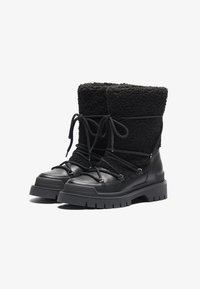 Botas negras con una base de cuero suave y un upper de forro polar texturizado. Suela de goma con surcos profundos; cordones ajustables para un mejor ajuste.