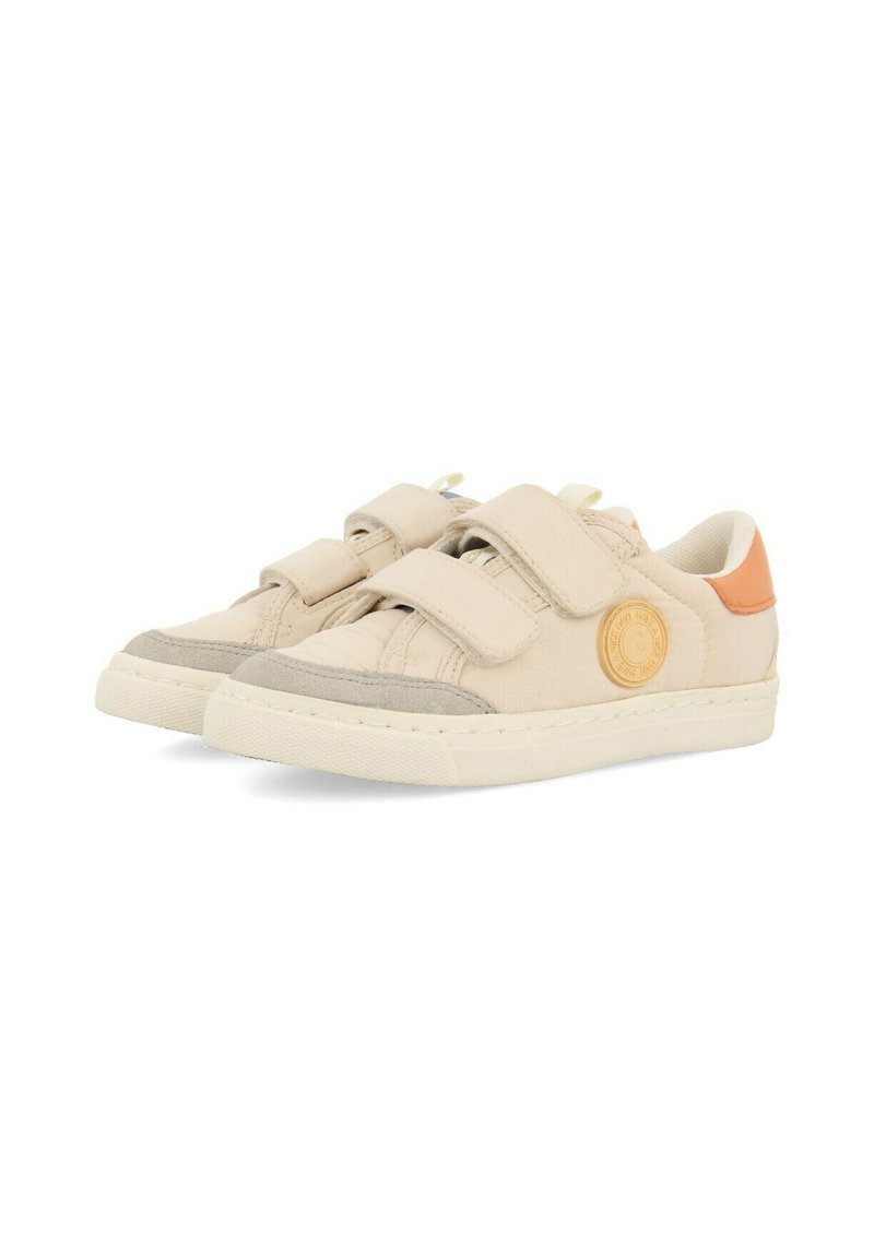 Zapatillas de lona beige con correas de velcro, acentos de ante gris, detalle de logo redondo y una etiqueta en el talón de color naranja contrastante. Suela de goma.