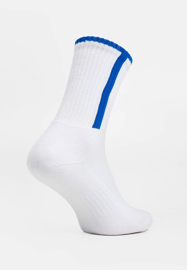 Calzino bianco a costine con bordino blu alla caviglia e striscia verticale blu lungo il lato, mostrato su una forma del piede contro uno sfondo semplice.