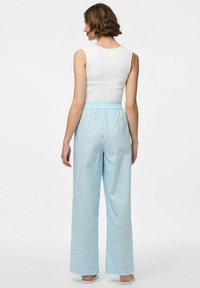 Lichtblauwe geruite pyjamabroek met een elastische tailleband, wijde pijpen en een zachte stoftextuur. De achteraanzicht toont het ontwerp en de pasvorm.