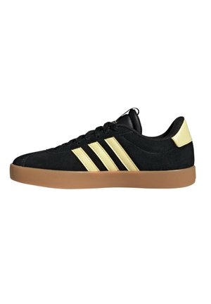 Zapatillas de ante negro con tres franjas doradas, que cuentan con una suela de goma y un cuello acolchado. Los cordones son negros, lo que resalta el diseño elegante.