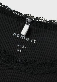 Čierny rebrovaný materiál s čipkovým lemovaním na výstrihu. Na štítku je značka "name it," veľkosť "2-3 roky" a rozmer "98."