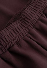 Marlotstof med en samlet elastisk talje, glat tekstur og blød finish, der viser plisserede detaljer hele vejen igennem.