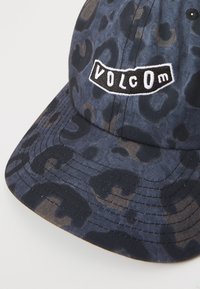 Cappellino blu navy con un motivo a stampa leopardata, dotato di un logo ricamato in nero "VOLCOM" sulla parte anteriore. Tessuto testurizzato e visiera curva.