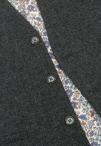Dark gray cardigan featuring textured fabric, four dark buttons, and a floral-patterned lining in blue, orange, and cream hues.
