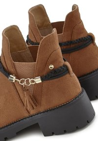 Rjave antilopne gležnjarje z elastiko na straneh, črnimi pletenimi akcenti, zlatim okovjem in debelimi črnimi gumijastimi podplati.