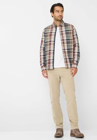Geruite blouse in rood, groen en blauw, gecombineerd met beige corduroy broek en bruine enkelboots. Witte t-shirt eronder.