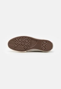 Sola de sapato de borracha castanha com padrão texturizado, apresentando formas de diamante e linhas. Inclui uma borda branca e detalhe de marca gravado.