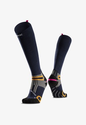 Paire de chaussettes de compression bleu marine montant jusqu'aux genoux avec des accents jaunes, gris, noirs et roses, vues de face et de dos sur fond blanc.