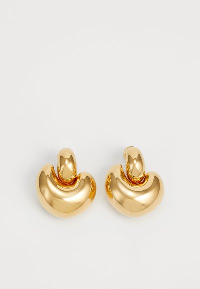 Goldfarbene Metallohrringe mit einer glatten, geschwungenen, abstrakten Form und einer polierten Oberfläche. Sie haben eine abgerundete Oberseite und einen konkaven Körper.