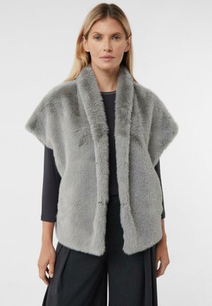 Szary kamizelka z sztucznego futra z szerokim kołnierzem i krótkimi rękawami, o miękkiej teksturze i otwartym designie z przodu. Noszona na czarnej bluzce i ciemnych spodniach.