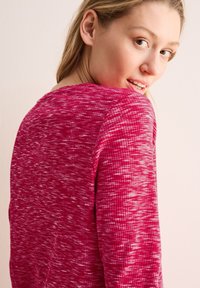 Langärmliges, strukturiertes Oberteil in leuchtendem Pink mit einem dezenten marmorierten Muster. Verfügt über einen runden Ausschnitt und einen lockeren Schnitt für optimalen Komfort.