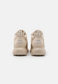 Beige sneakers met een ronde uitstraling, een gladde synthetische bovenkant, een gestructureerde rubberen zool en een subtiele logo-detail op de hiel.