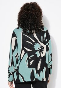 Cardigan lavorato a maglia floreale in teal, nero e crema con motivi di fiori oversize; presenta una vestibilità ampia e maniche lunghe.