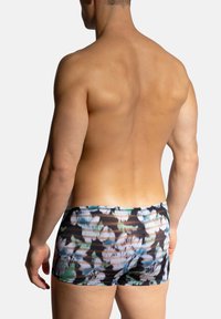 Herrarnas badshorts med ett flerfärgat abstrakt mönster, tillverkade av ett mjukt tyg. Låg midja med en åtsittande design och elastisk midjeband.