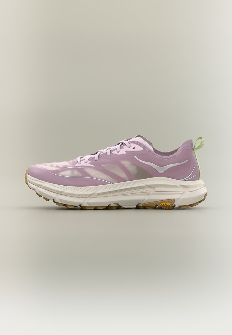 Αθλητικό παπούτσι σε ανοιχτό μοβ χρώμα με λευκή σόλα, μπεζ εξωτερική σόλα Vibram, λευκό λογότυπο και πράσινη ταινία έλξης στη φτέρνα, σε ουδέτερο φόντο.