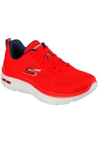 Zapatilla deportiva roja con parte superior de malla, suela blanca y superficie texturizada. Cuenta con cordones y un cuello en contraste de color azul marino.