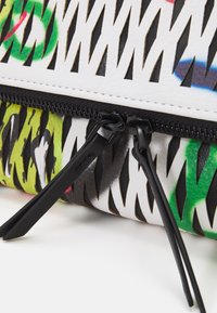 Multifarvet læderpung med en tekstureret overflade, der har sort lynlås og intrikate udskæringsmønstre med hvide og grønne accenter.