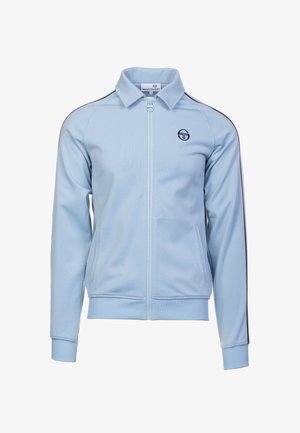 Lichtblauwe ritsjack gemaakt van glad materiaal. Heeft een staande kraag, zijzakken en marineblauwe accenten langs de schoudernahts. Logo op de borst.