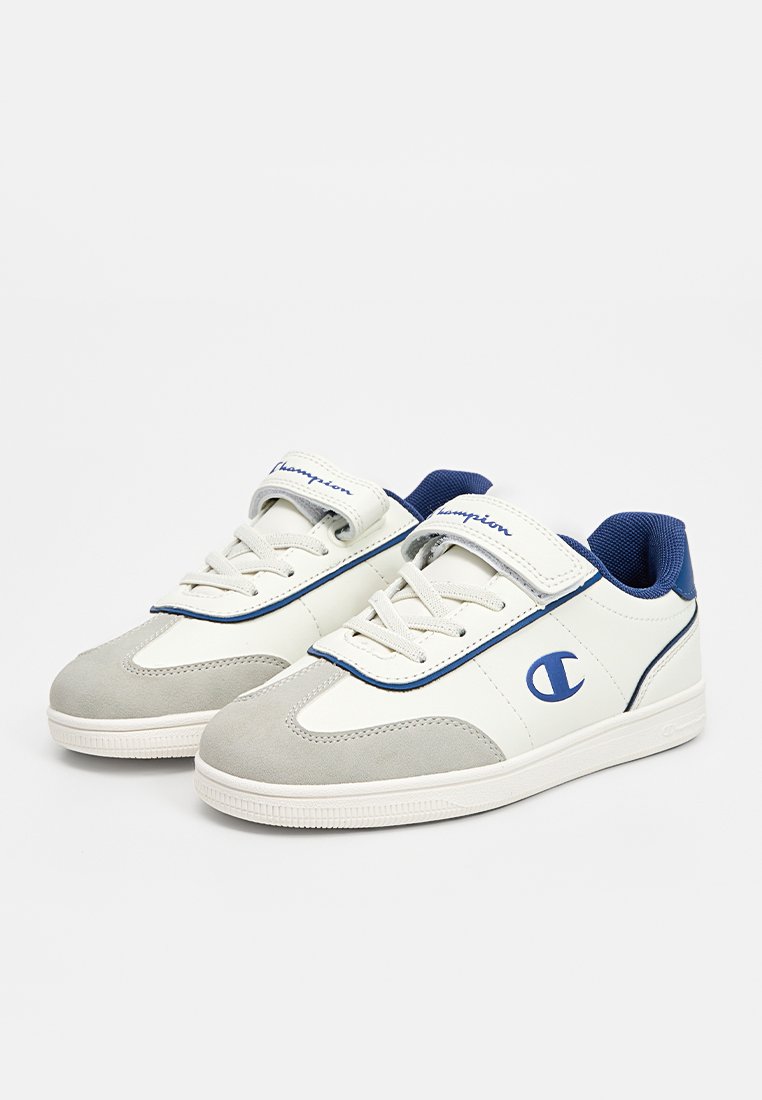 Baskets blanches et grises avec une tige en cuir lisse et des accents en daim, présentant un logo bleu et une sangle Velcro sur des lacets traditionnels.