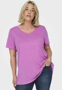 T-shirt a manica corta con scollo a V di un leggero colore viola, realizzato in tessuto morbido. Il design presenta una vestibilità comoda con una leggera curvatura all'orlo.