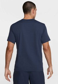 Navy blue cotton t-shirt with short sleeves, a classic crew neck, and a smooth texture. No visible patterns or accents. Rear view shown.