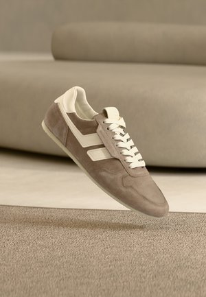 Αθλητικά παπούτσια από σουέτ σε ανοιχτό καφέ με λευκές λεπτομέρειες. Διαθέτουν σχέδιο με κορδόνια, υφή στο επάνω μέρος και λαστιχένια σόλα. Μινιμαλιστική αισθητική.