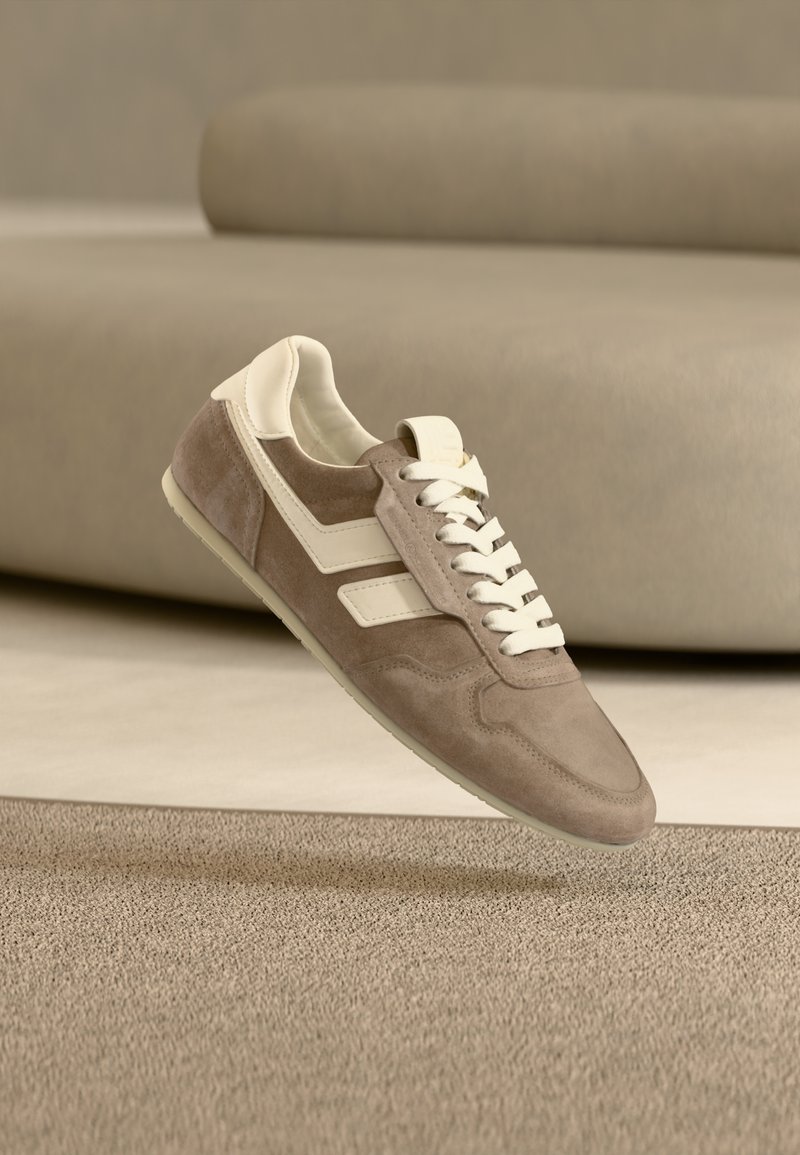 Αθλητικά παπούτσια από σουέτ σε ανοιχτό καφέ με λευκές λεπτομέρειες. Διαθέτουν σχέδιο με κορδόνια, υφή στο επάνω μέρος και λαστιχένια σόλα. Μινιμαλιστική αισθητική.