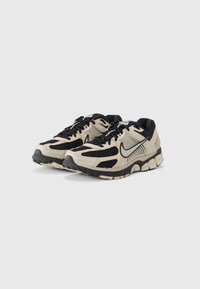 Μπεζ και μαύρα αθλητικά παπούτσια με υλικό από δίχτυ, επενδεδυμένο κολάρο, υφή στην εξωτερική σόλα και εμφανές λογότυπο στο πλάι.