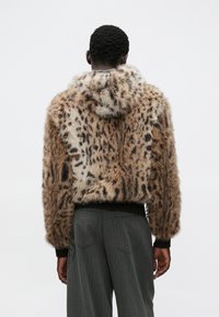 Kurtka z futerka sztucznego o wzorze w panterkę, z kapturem i dzianinowymi mankietami, zaprojektowana z krótkim krojem i miękką teksturą.