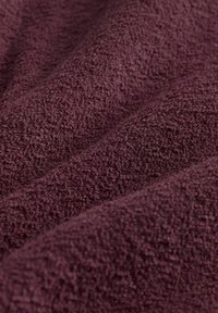 Burgundy struktureret stof med en blød, plyssede overflade og subtile bølgemønstre. Ideelt til polstring eller dekorative formål.