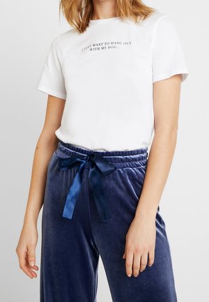 Valkoinen puuvillainen t-paita, jossa mustat tekstit "Haluan vain viettää aikaa koirani kanssa." Yhdistetty tummansinisiin samettihousuihin, joissa satiininauha.