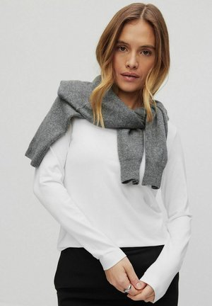 Gray knit scarf draped over a white long-sleeve top. The scarf has ribbed ends and a soft texture, lending a casual, layered look.