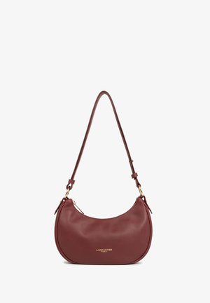 Sac à épaule en cuir rouge avec une forme incurvée, accents en matériel doré et logo embossé. Dispose d'une seule sangle réglable et d'une fermeture zippée.